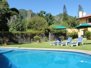 una piscina con 2 sillas y sombrillas en Las Casitas Tepoztlán, en Tepoztlán