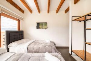 1 dormitorio con 2 camas y TV en la pared en La villa de san Juan, en Villa de Leyva