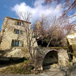 un edificio de piedra con un árbol delante de él en La Fontaine, en Bargème