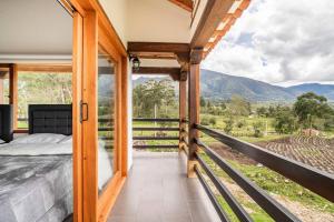 1 dormitorio con 1 cama y balcón con vistas. en La villa de san Juan, en Villa de Leyva