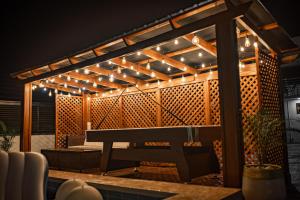a patio with a bench under a pergola with lights at Cloud9 Luxury Apartments in Accra