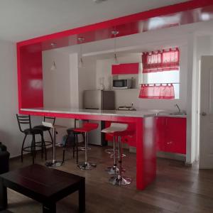 una cocina con armarios rojos y taburetes de bar en Hotel Halley en León