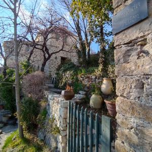 a stone wall with a fence and some plants at La Fontaine in Bargème