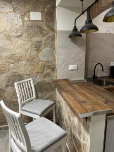 a kitchen with two chairs and a stone wall at Consolación17 in Cáceres
