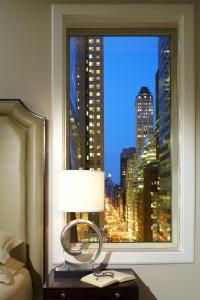 a bedroom with a window with a view of a city at Omni Berkshire Place in New York