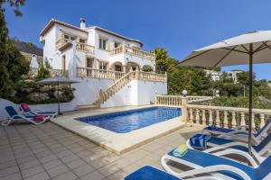 a villa with a swimming pool with chairs and an umbrella at Casa Thalassa in Balcon del Mar