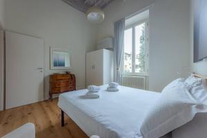 een witte slaapkamer met een groot bed en een raam bij Borgo Pinti's Duplex Apartment in Florence