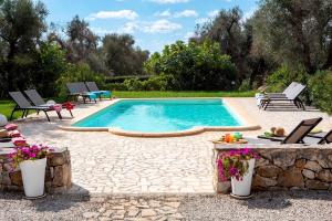 a swimming pool in a yard with chairs and a table at Trullo Bouganville in San Michele Salentino