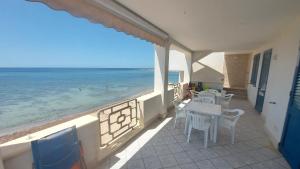 balcone con tavoli, sedie e vista sull'oceano di 058 Spiaggia di SalentoInVacanza.Com a Torre Pali
