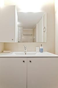 ein weißes Badezimmer mit einem Waschbecken und einem Spiegel in der Unterkunft ARGO SWEET HOME close by the city center in Iraklio