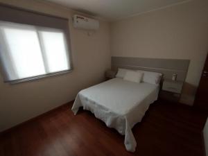 a bedroom with a white bed and a window at Casa Capri Salta in Salta