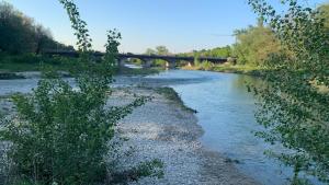 a river with a bridge in the background at Attico con terrazzo. in Parma