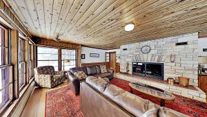 - un salon avec un canapé et une cheminée en pierre dans l'établissement George's Lakeside Haven on Lac Courte Oreilles, à Stone Lake
