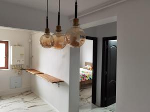 a hallway with three glass lights hanging from the ceiling at Apartament Garofitei in Constanţa