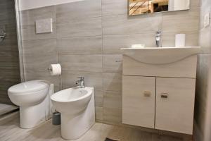 ein Badezimmer mit einem WC, einem Waschbecken und einem Spiegel in der Unterkunft La Corte di Vincenzo in Noto