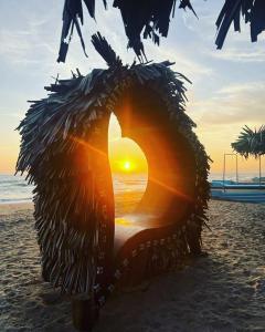a view of a sunset in a straw hut on the beach at Mithra Paradise Beach Hotel in Nilaveli