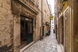 an alley with buildings and a person sitting on a bench at Old Town Apartment Paulina in Dubrovnik