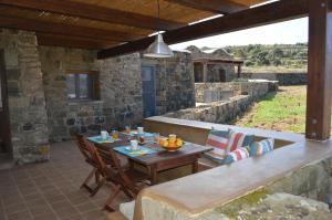 a patio with a wooden table and chairs on a porch at I DAMMUSI DEL VENTO in Pantelleria +21 photos