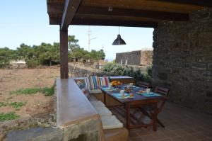 a patio with a table and chairs and a bench at I DAMMUSI DEL VENTO in Pantelleria