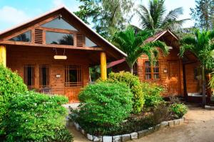 uma casa de madeira com arbustos à frente em Mithra Paradise Beach Hotel em Nilaveli