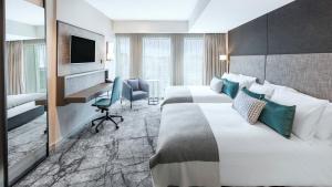 a hotel room with two beds and a desk and a television at Crowne Plaza Christchurch by IHG in Christchurch