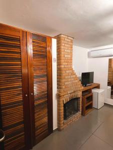 a living room with a brick fireplace and a desk at Hotel Bertell in Penedo