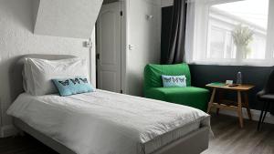 a bedroom with a bed and two green chairs at Orient B&B in Holyhead