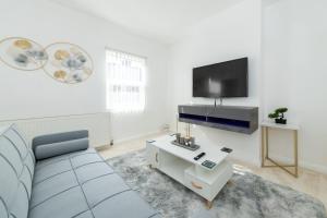 a living room with a couch and a flat screen tv at Favourite by couple and group of 3 Cosy Apartment Close to City Centre in Reading