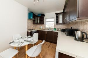 a kitchen with a table and white chairs in it at Favourite by couple and group of 3 Cosy Apartment Close to City Centre in Reading