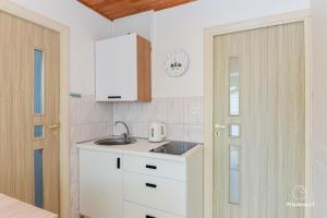 a white kitchen with a sink and a door at RAMYBĖS OAZĖ 2 in Šventoji +8 photos