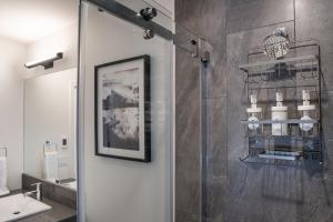 a bathroom with a shower with a sink and a mirror at Peaks and Birdies by Revelstoke Vacations in Revelstoke