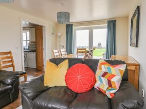 a living room with a black leather couch with pillows at Drosgl in Llangefni