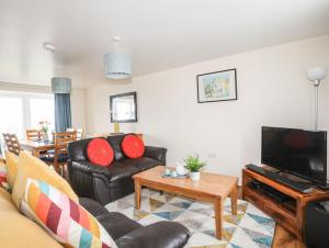 a living room with black leather furniture and a flat screen tv at Drosgl in Llangefni