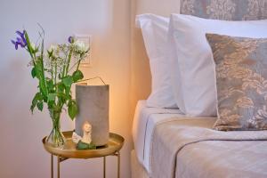 a vase of flowers on a table next to a bed at Anesis Studios Old Corfu Town in Corfu