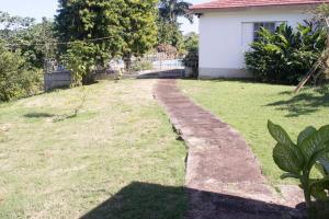 a path in a yard next to a house at Country Side Cottages in Oracabessa