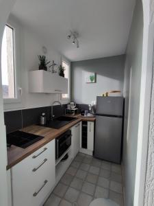 una pequeña cocina con armarios blancos y nevera. en studio meublé classé 2 étoiles - 30m², en Gréoux-les-Bains