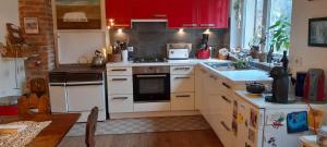 uma cozinha com electrodomésticos brancos e armários vermelhos em La chambre rose em Rosenwiller