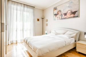 sypialnia z białym łóżkiem i dużym oknem w obiekcie Morgantini House San Siro-Duomo "Netflix & Terrace" w Mediolanie