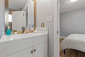 a white bathroom with a sink and a bed at Elegant Boho Retreat - 8 min to WEM in Edmonton