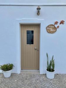 a door of a white building with two potted plants at Casa Pedra Rosa - VINHAS de NEXE in Faro