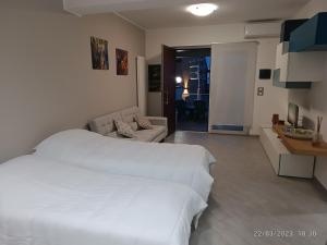 ein Schlafzimmer mit einem weißen Bett und ein Wohnzimmer in der Unterkunft Tra cielo e mare in Capo dʼOrlando