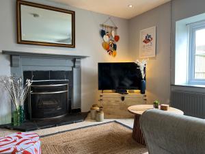 sala de estar con chimenea y TV de pantalla plana en Spacious 4 Bedroom Farmhouse, en Pembrokeshire