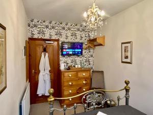 a bedroom with a bed and a dresser and a chandelier at Elm Tree Lodge in Keswick