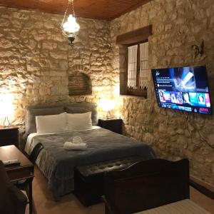 SeaFront Stone Suites في فونيتسا: غرفة نوم بسرير وتلفزيون بشاشة مسطحة