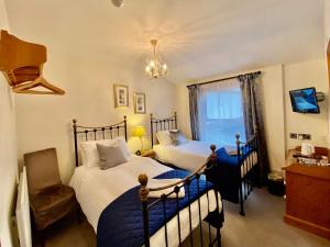 a bedroom with two beds and a chandelier at Elm Tree Lodge in Keswick