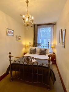 1 dormitorio con 1 cama con lámpara de araña y ventana en Elm Tree Lodge, en Keswick