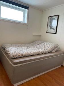 1 cama en un dormitorio con ventana en Sentral og koselig leilighet, en Tromsø
