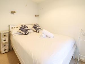 uma cama branca com almofadas e uma toalha em Ty Cornel em Aberdyfi