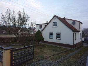 a white house with a fence in front of it at Auf dem Land und doch ganz nah (EG) in Krölpa
