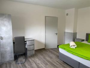 a bedroom with a bed and a desk with a green blanket at Auf dem Land und doch ganz nah (EG) in Krölpa